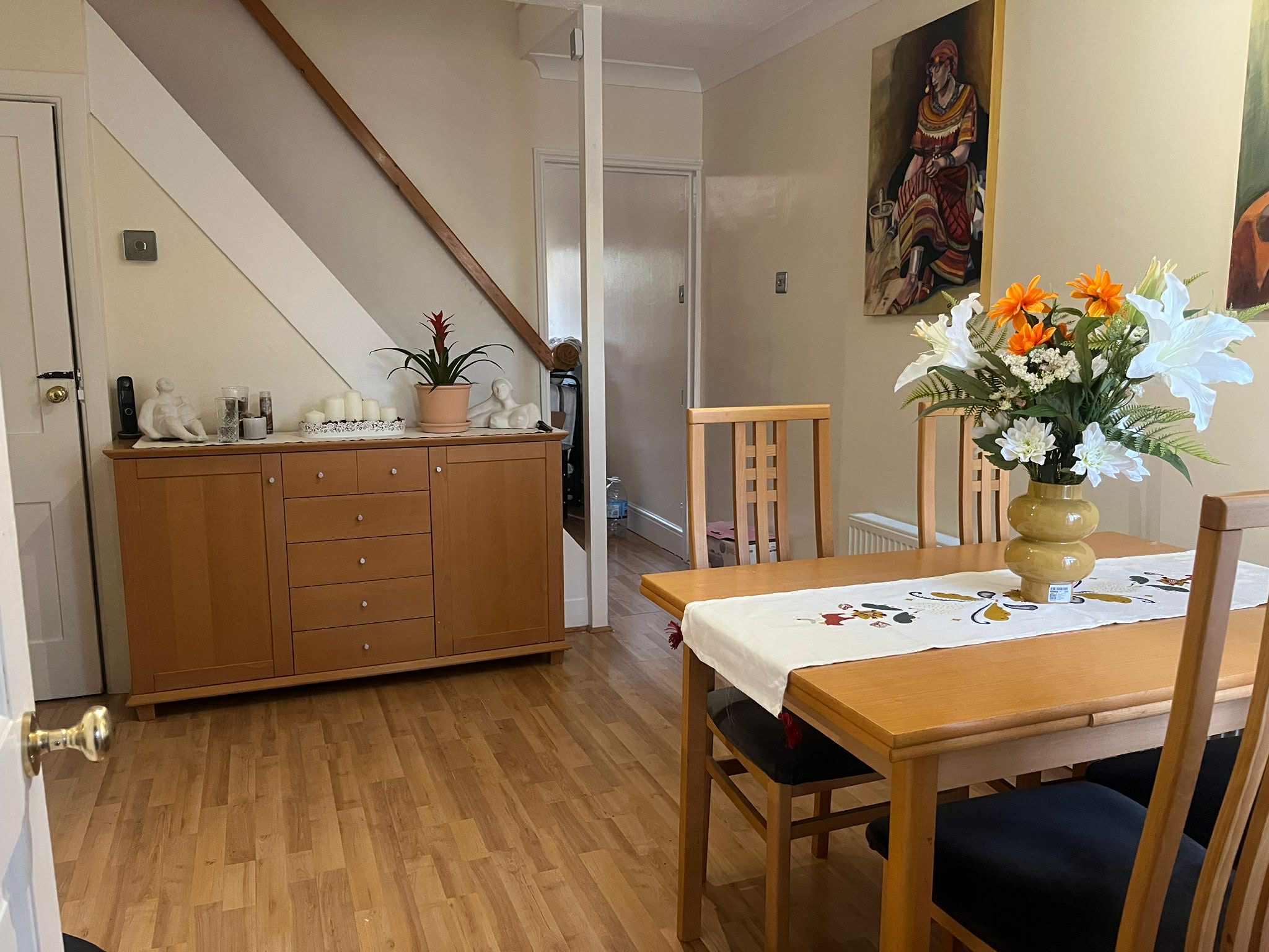 Finished dining room with light walls, wooden furniture and floral arrangement