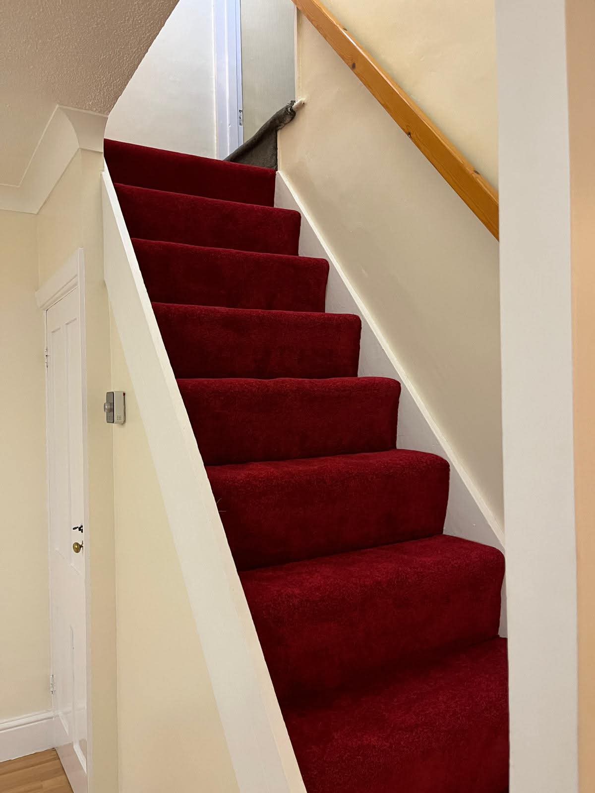 Freshly decorated staircase with light walls and red carpet